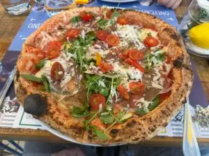 Pizza Capri Blu con jamón serrano, rúcula, tomate cherry y láminas de parmesano.